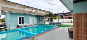 a swimming pool with a blue house with an awning at Triple S Homestay Bachok in Bachok