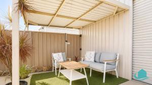 a patio with a couch and a table and chairs at Coastal Hideaway at Pelican in Pelican Flat