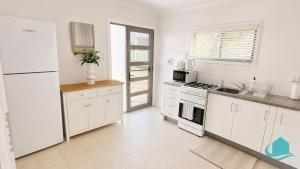 a kitchen with white cabinets and a white refrigerator at Coastal Hideaway at Pelican in Pelican Flat