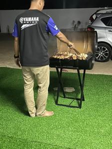 a man is cooking food on a grill at Triple S Homestay Bachok in Bachok