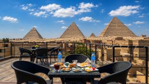 a table with food on a balcony with a view of pyramids at Pyramids Front Gate Hotel in Cairo