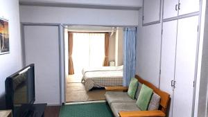 a room with a bed and a couch and a television at Near Tram Apartment Okayama in Okayama
