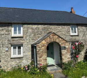 a stone house with a green door and flowers at Rose Cottage in Wadebridge
