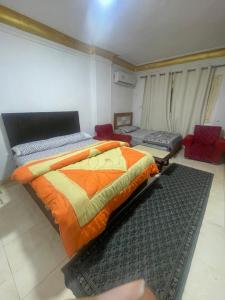 a bedroom with a bed with an orange comforter at Pyramids Heritage suites in Ghaţāţī