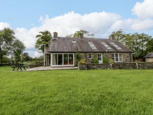 an old stone cottage with a grass field in front of it at Bryn Isaf in Ystrad Meurig