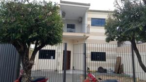 a house behind a fence with trees in front of it at Pousada Exclusiva in Rondonópolis
