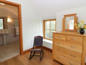 a bedroom with a dresser and a mirror and a chair at Bryn Isaf in Ystrad Meurig +41 photos