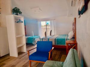 a room with two beds and a blue chair at Zurisadai in Puerto Ayora