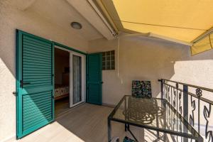 a balcony with green doors and a glass table at Beachside Villa Mia Apartments in Medveja