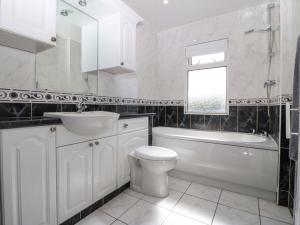 a white bathroom with a sink and a tub and a toilet at Gwynfa in Colwyn Bay +23 photos