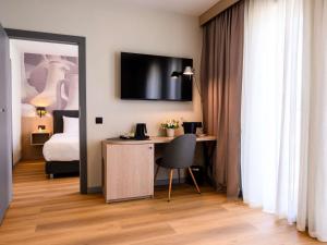 a room with a desk and a bed and a television at Mercure Alba Iulia in Alba Iulia