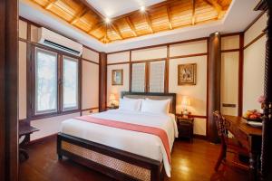 a bedroom with a bed and a desk and windows at Phoum Chaufea Resort in Siem Reap