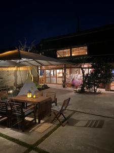 a table and chairs under an umbrella at night at 蔵Mping Hotel in Fukaya