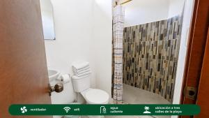 a small bathroom with a toilet and a shower at Suites Villa Colombia in Puerto López