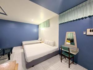 a bedroom with a bed and a table and a chair at โรงแรม วี เฮาส์ ณ คอน in Nakhon Si Thammarat