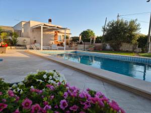 a swimming pool with flowers in front of a house at VILLA SESIFE Avola in Avola