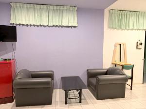 a living room with two chairs and a table at โรงแรม วี เฮาส์ ณ คอน in Nakhon Si Thammarat