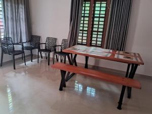 a table and chairs and a bench in a room at Wayanad One in Wayanad