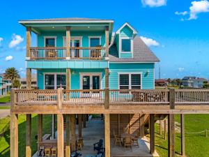 a blue house with a deck on a beach at The Elevated Spoonbill Dog-Friendly Beach Retreat in Bolivar Peninsula