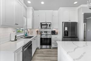 a kitchen with white cabinets and stainless steel appliances at The Elevated Spoonbill Dog-Friendly Beach Retreat in Bolivar Peninsula