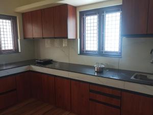 a kitchen with wooden cabinets and a sink and windows at Dream Stay in Varkala