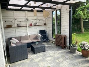 a patio with a couch and a table at Cozy Cottage Close To The Beach in Bogense
