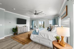 a bedroom with a large bed with a ceiling fan at The Elevated Spoonbill Dog-Friendly Beach Retreat in Bolivar Peninsula