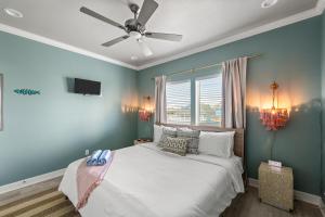 a bedroom with a white bed with a ceiling fan at The Elevated Spoonbill Dog-Friendly Beach Retreat in Bolivar Peninsula