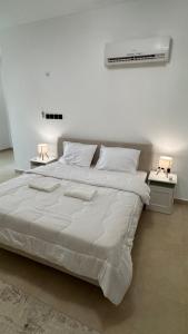 a bedroom with a large white bed with two lamps at The Inn Salalah in Salalah +9 photos