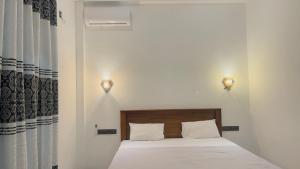 a bedroom with a bed with two lights on the wall at Ck resort in Weligama