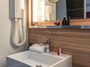 a white sink in a bathroom with a mirror at IBIS STYLES ALES CENTRE in Alès +57 photos