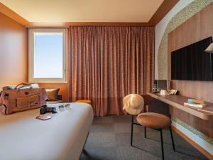 a hotel room with a bed and a desk at IBIS STYLES ALES CENTRE in Alès