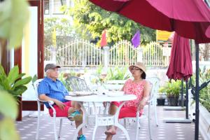 two people sitting at a table under an umbrella at Phasouk Vien Chantra Hotel in Vientiane