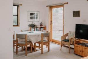 a dining room with a table and chairs and a television at Whalers Cottage in Port Fairy