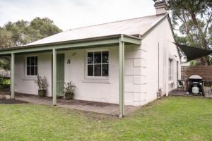 a white house with a porch and a table at Whalers Cottage in Port Fairy