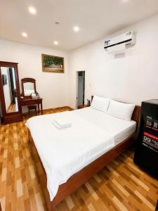 a bedroom with a large white bed and a desk at KS Phương Danh in Quy Nhon