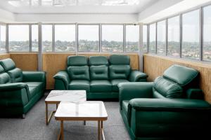 a waiting room with green furniture and large windows at Beal Mall & Hotel in Arua