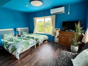 a blue bedroom with two beds and a window at Sun Ocean Hachijojima in Hachijo