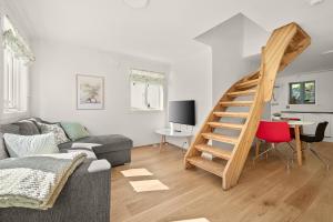 a living room with a couch and a wooden staircase at Hagehuset in Kragerø