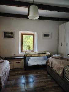 a room with two beds and a table with a window at Etno house HAPPY VILLAGE in Cetinje