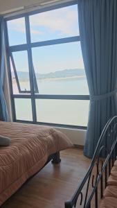 a bedroom with a large window with a view of the water at Swiss belhotel apartment in Kuantan