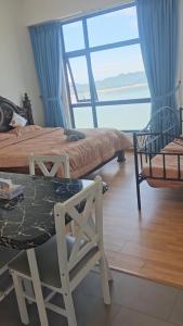 a bedroom with two beds and a large window at Swiss belhotel apartment in Kuantan