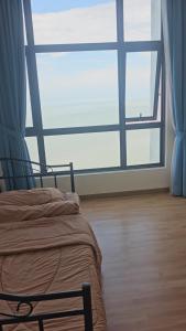 a bed in a room with a large window at Swiss belhotel apartment in Kuantan