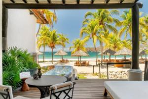 a patio with a view of the beach and palm trees at Thompson Zihuatanejo, A Beach Resort, by Hyatt in Zihuatanejo