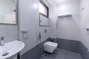 a white bathroom with a toilet and a sink at Lumis Beach Hotel in Visakhapatnam +10 photos