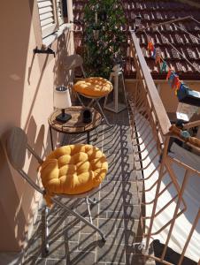 ein Balkon mit Stühlen und einem Hocker darauf in der Unterkunft Angelos Apartment in Vathy