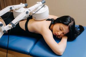 a woman is laying on a bed with a machine at HOTEL CRYSTAL WELLNESS & SPA superior in Sovata +179 photos