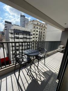 a table and chairs on a balcony with a view of a city at Setin Downtown | Conforto no Centro de SP in São Paulo