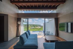 a living room with a blue couch and a large window at Villa Azure Mira in Miyakojima