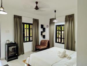 ein Schlafzimmer mit Bett, Stuhl und Fenstern in der Unterkunft The Double V Experience in Arambol